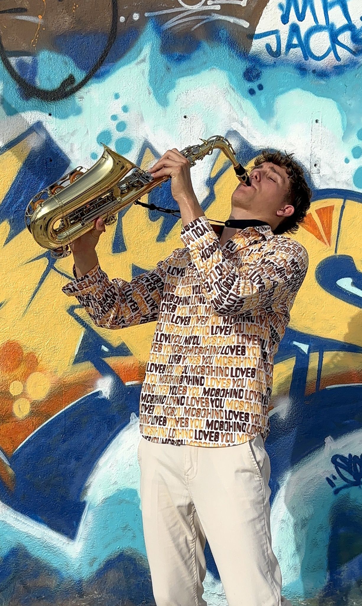 Kian Kazàn performing in front of a colourful graffiti wall